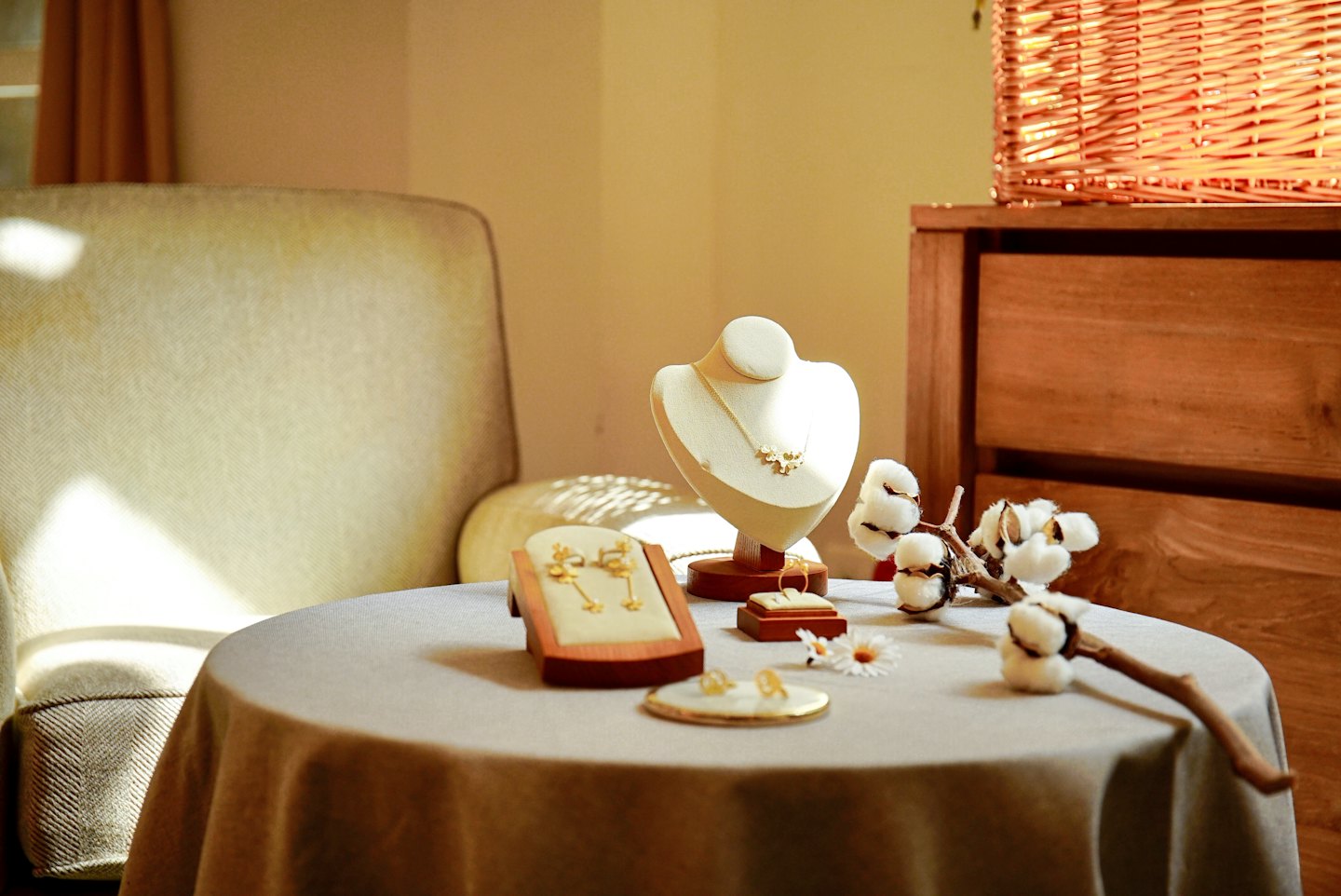 Gold jewelry displayed on a table with flowers.
