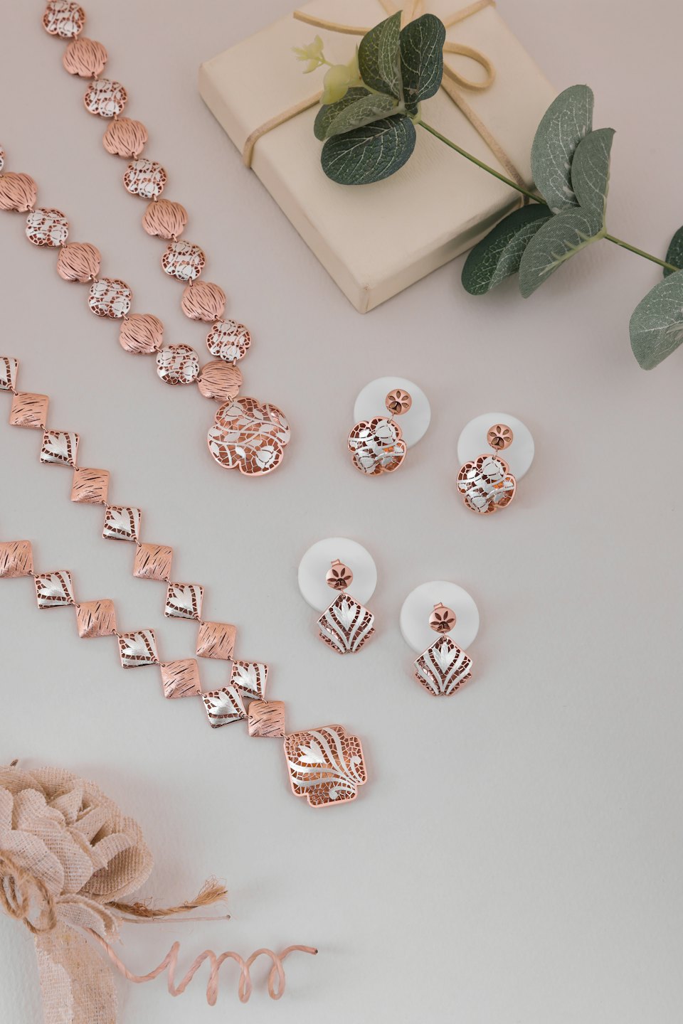 Rose gold and silver jewelry with gift box and eucalyptus.