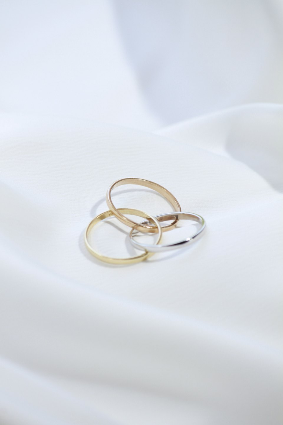 Three gold rings interlocking on white fabric.